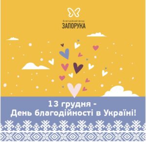 Ілюстрація з жовтим фоном, на якій летять різнокольорові сердечка. Напис: "13 грудня — День благодійності в Україні". Логотип фонду «Запорука» зверху.