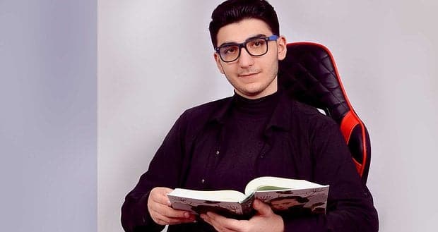Хлопець у чорному одязі з окулярами сидить на кріслі з книжкою в руках — учасник благодійного забігу на підтримку дітей з онкологією.